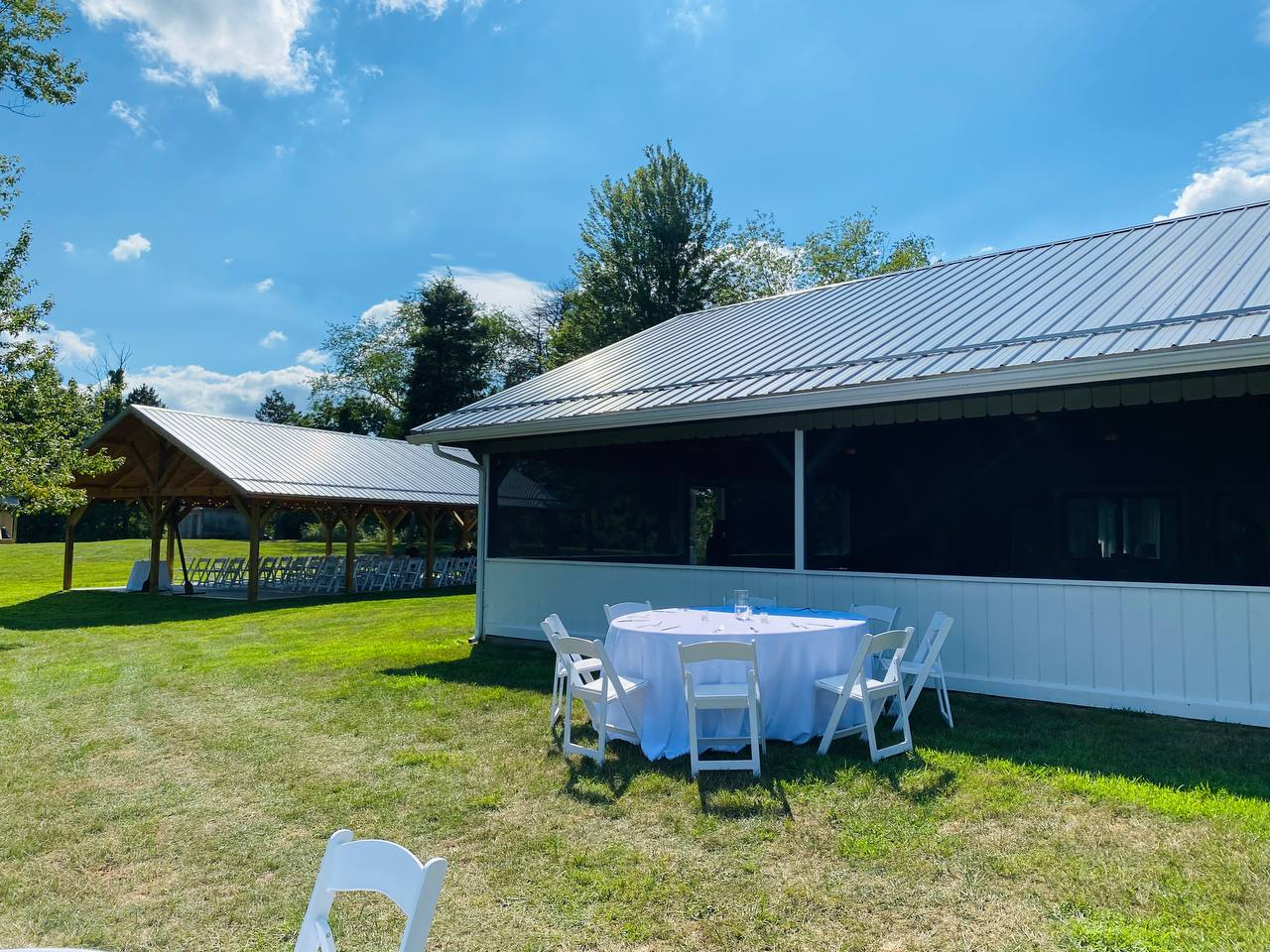 Screened lake house porch with a reception table on the lawn beside the pavilion