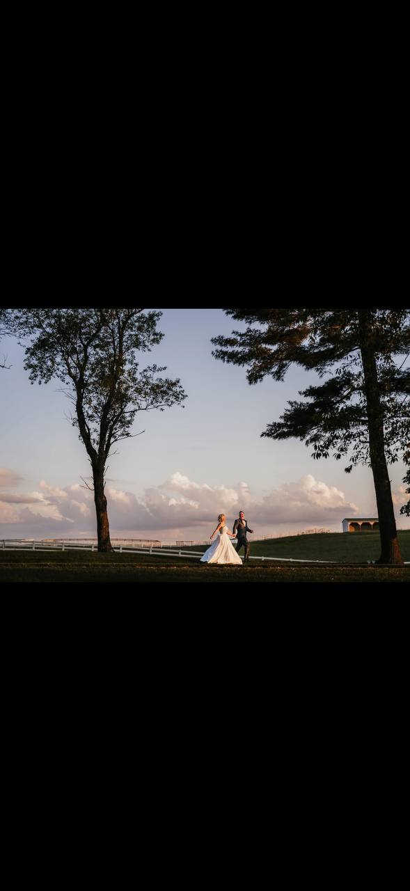 Bride and groom walking together at sunset between estate trees