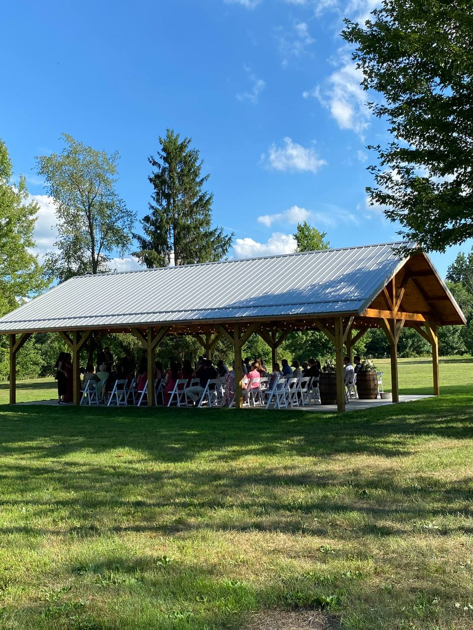 Wedding guests seated in the open-air pavilion on a sunny summer afternoon