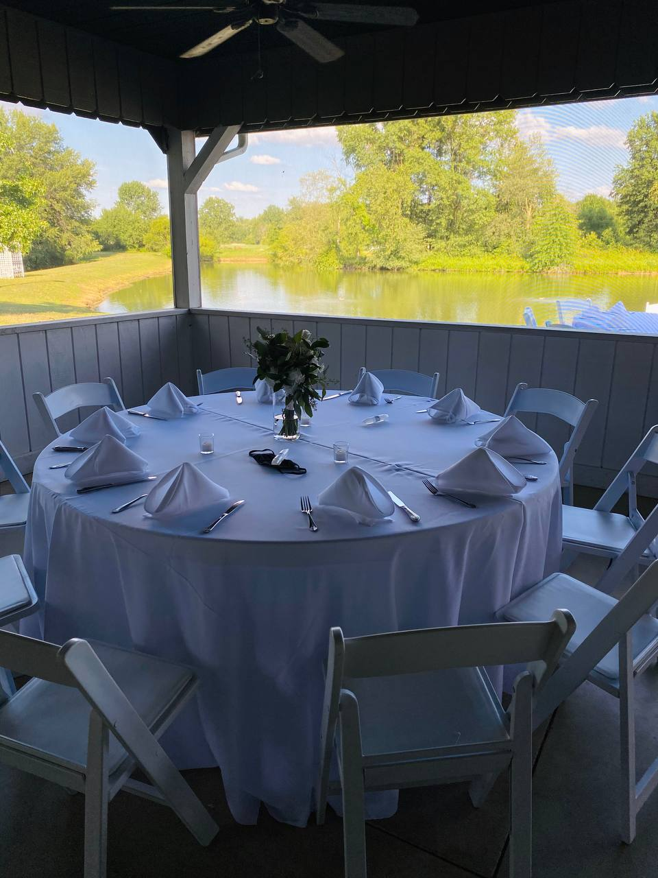 Round reception table set with white linens in the lakeside gazebo