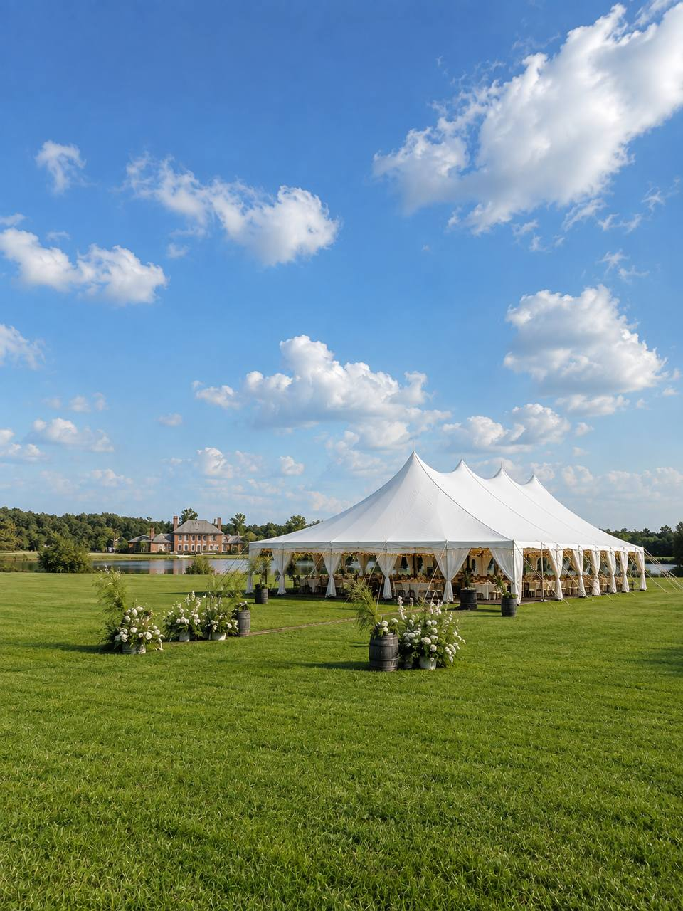 White reception tent set on the lawn above the lake under summer skies