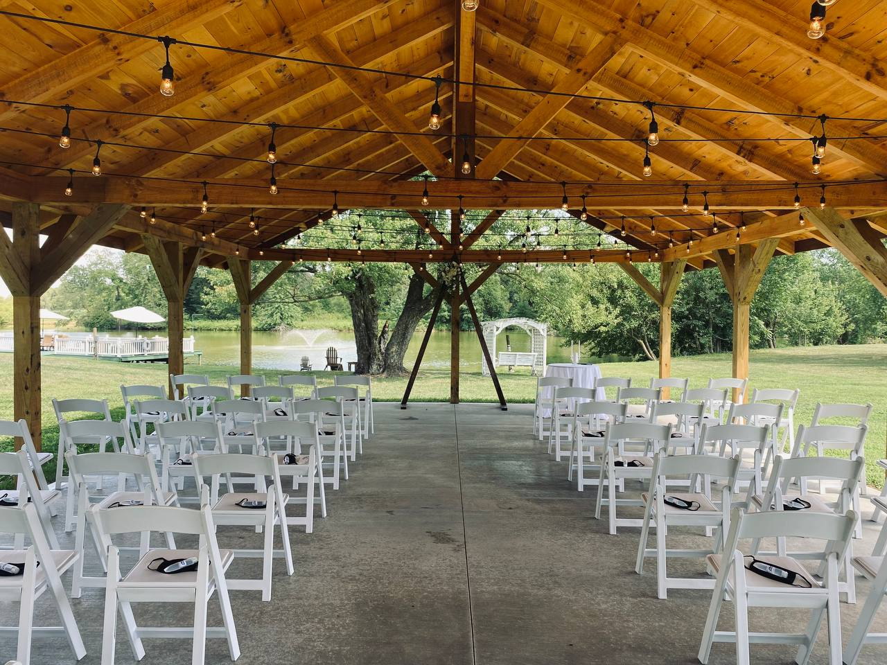 Pavilion ceremony aisle framing the lake, fountain and white arbor