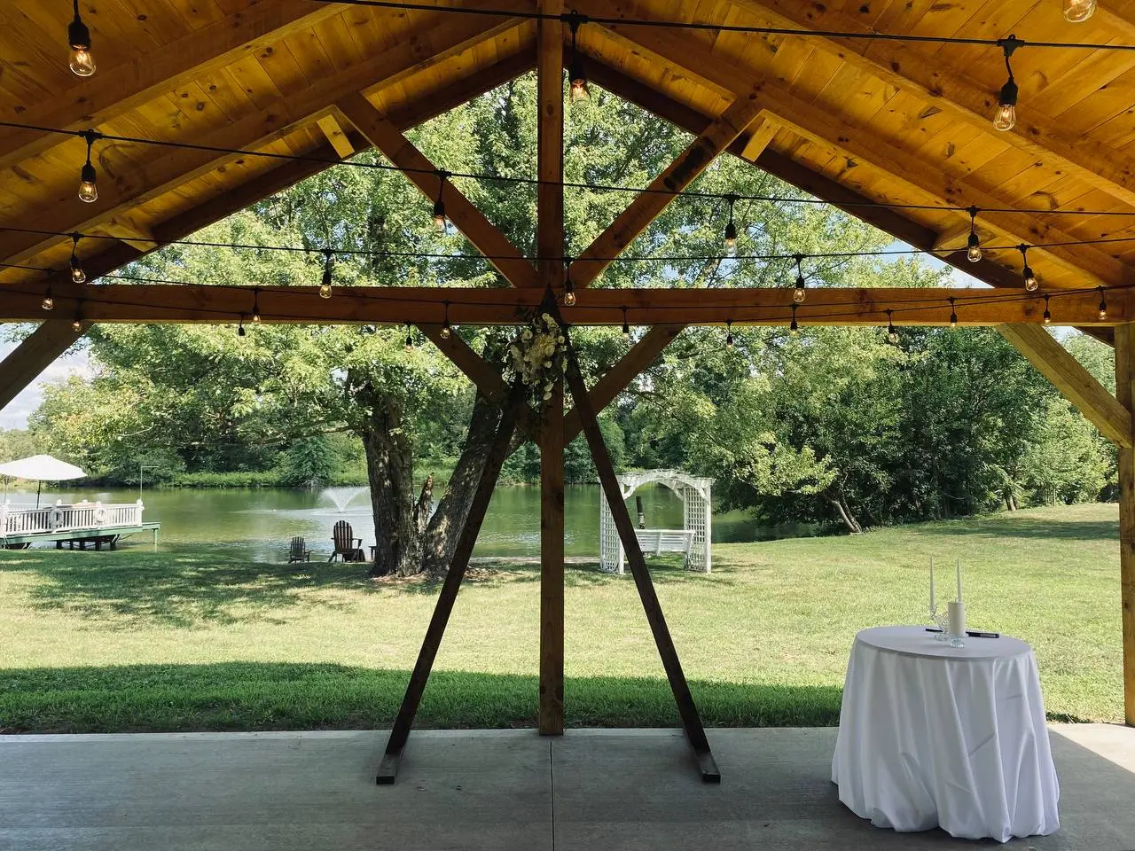 View of the lake, fountain and white arbor framed by the pavilion beams