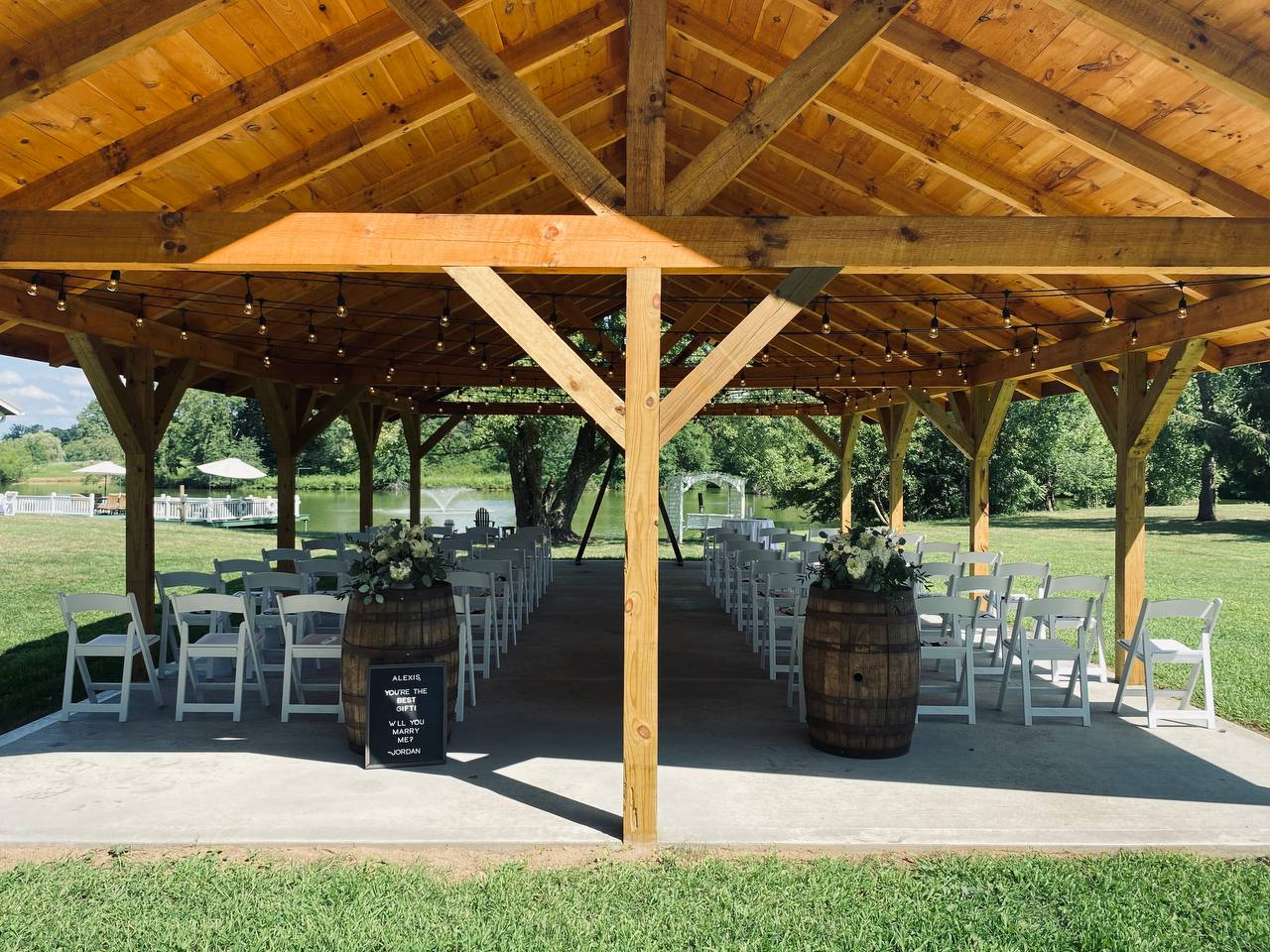 Ceremony aisle under the pavilion with whiskey barrels and floral arrangements