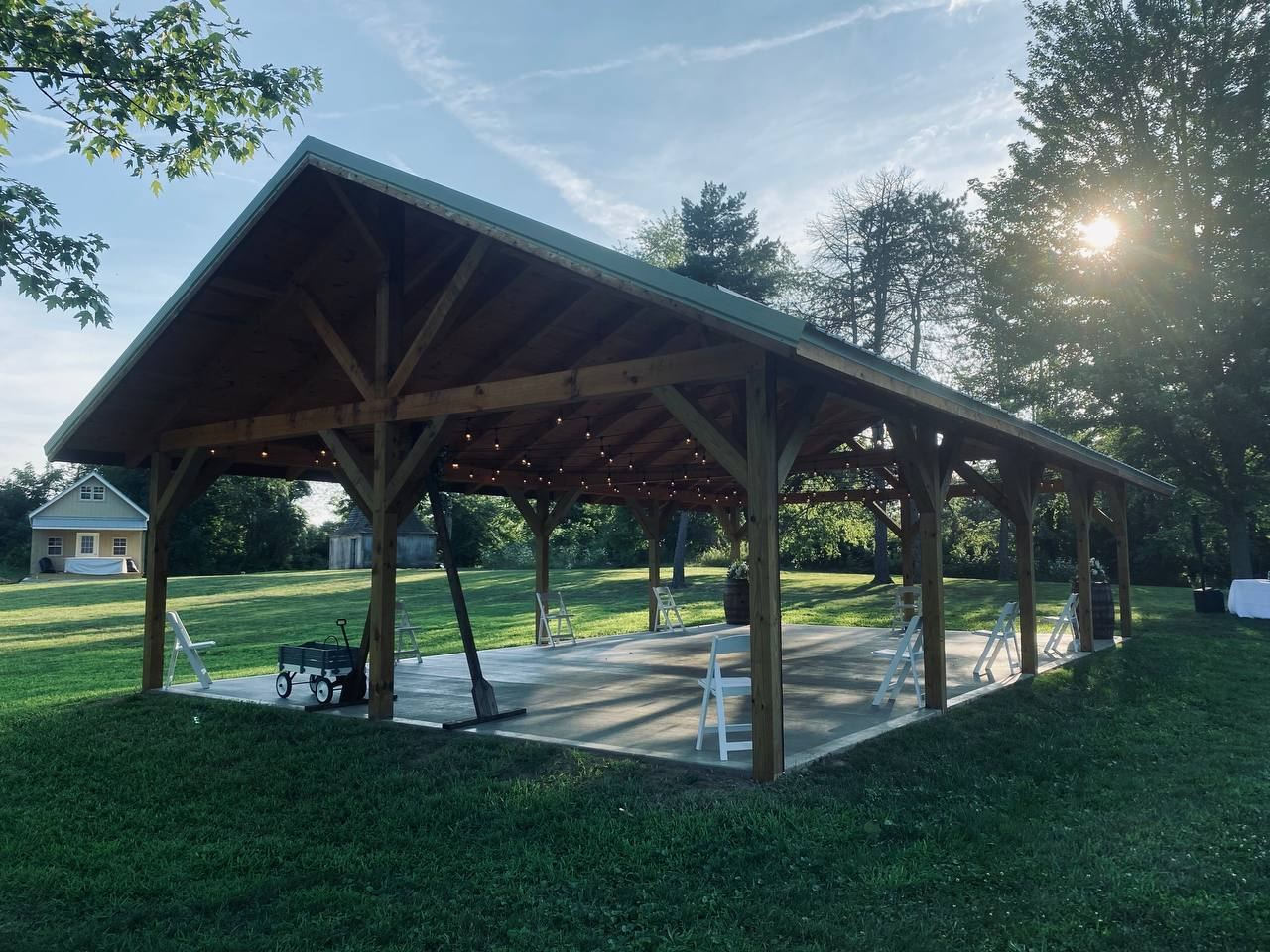 The timber pavilion at golden hour with string lights and folding chairs