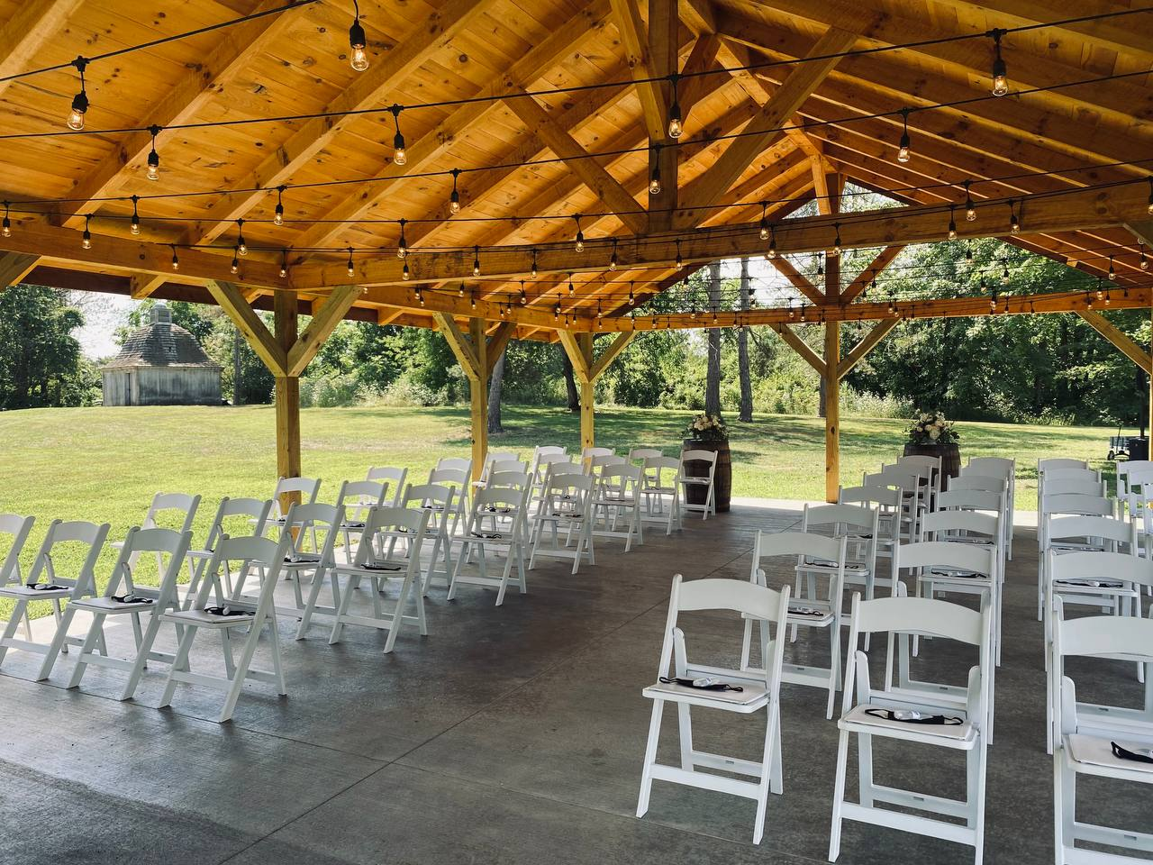 Ceremony chairs and barrel florals under the pavilion beside the open lawn