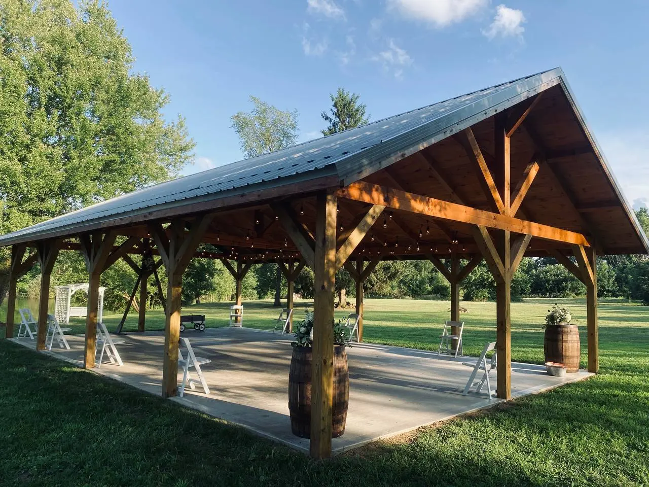 Sunlit pavilion interior with whiskey barrel florals and Edison string lights