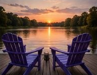 Two purple Adirondack chairs facing the lake at sunset