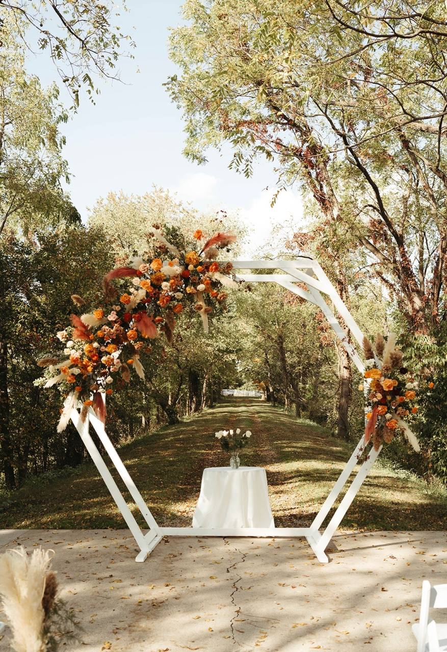 White hexagon arbor with autumn florals and pampas at the end of the tree lane