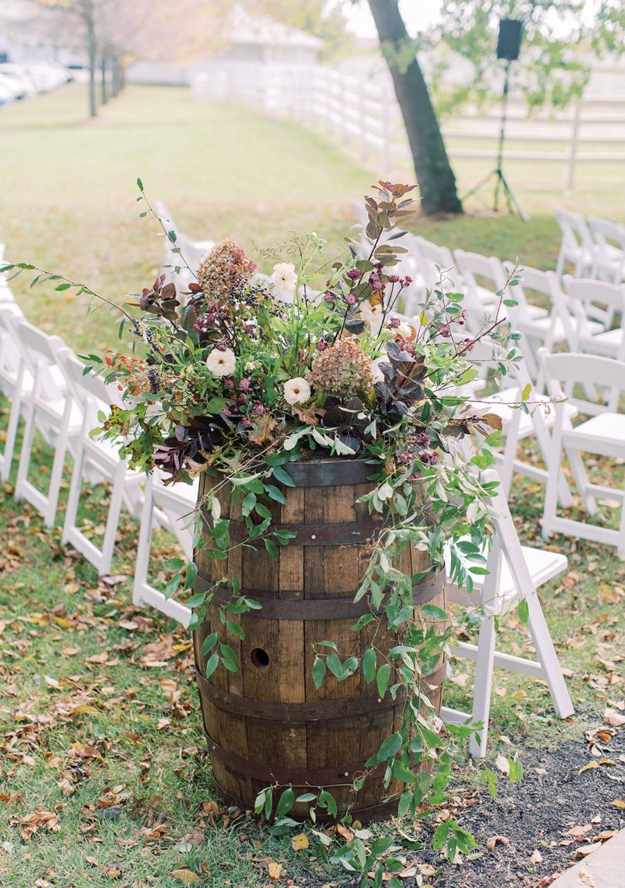 Autumn barrel arrangement of hydrangea and trailing greenery along the aisle